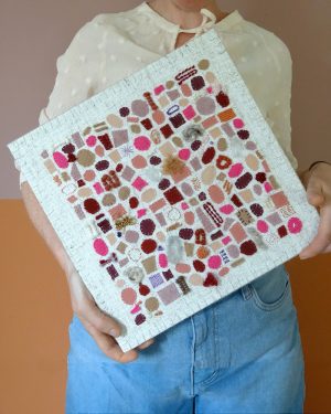 Dit werk heet Zoet zomerfruit en is 30x30 cm. Zoet zomerfruit is een herinnering aan zomerse dagen met een gouden randje. Annemieke heeft het werk schuin in haar handen.