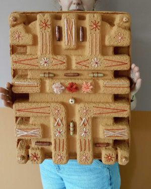 Tastbare tray met reliëf die voelbaar kunstwerk toont. De tray heeft een terra kleur en er is op geborduurd. Annemieke heeft de tray in haar handen.